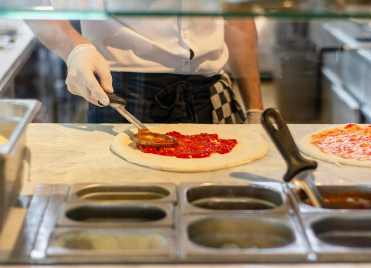 A person behind a counter making a pizza